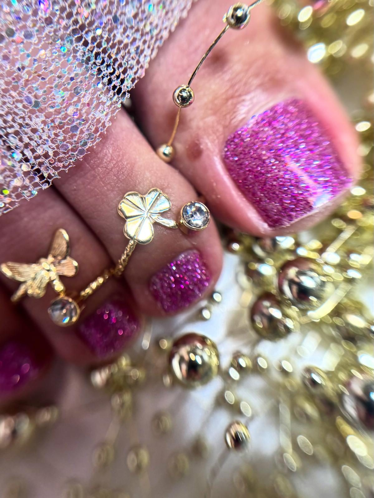 Kosmetische Fußpflege: pinker Glitzerlack mit goldenem Zehenschmuck